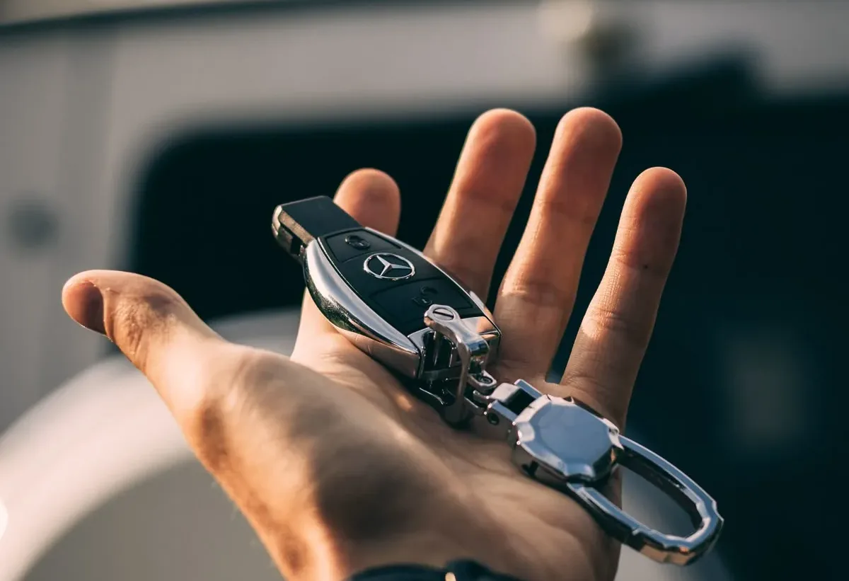 Automotive keys and a remote fob held in a customer’s hand.